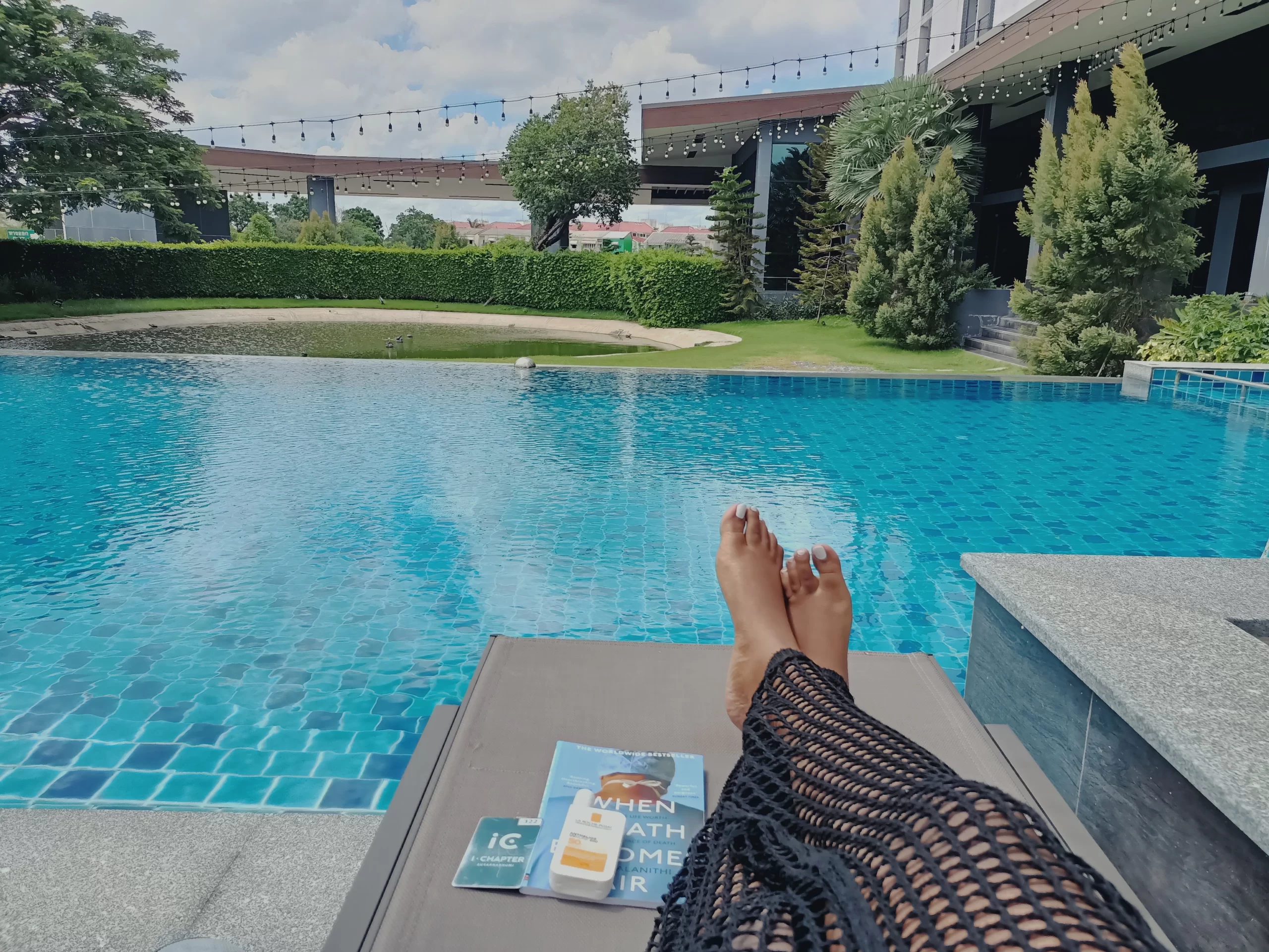 woman laying by a pool with book practicing self care